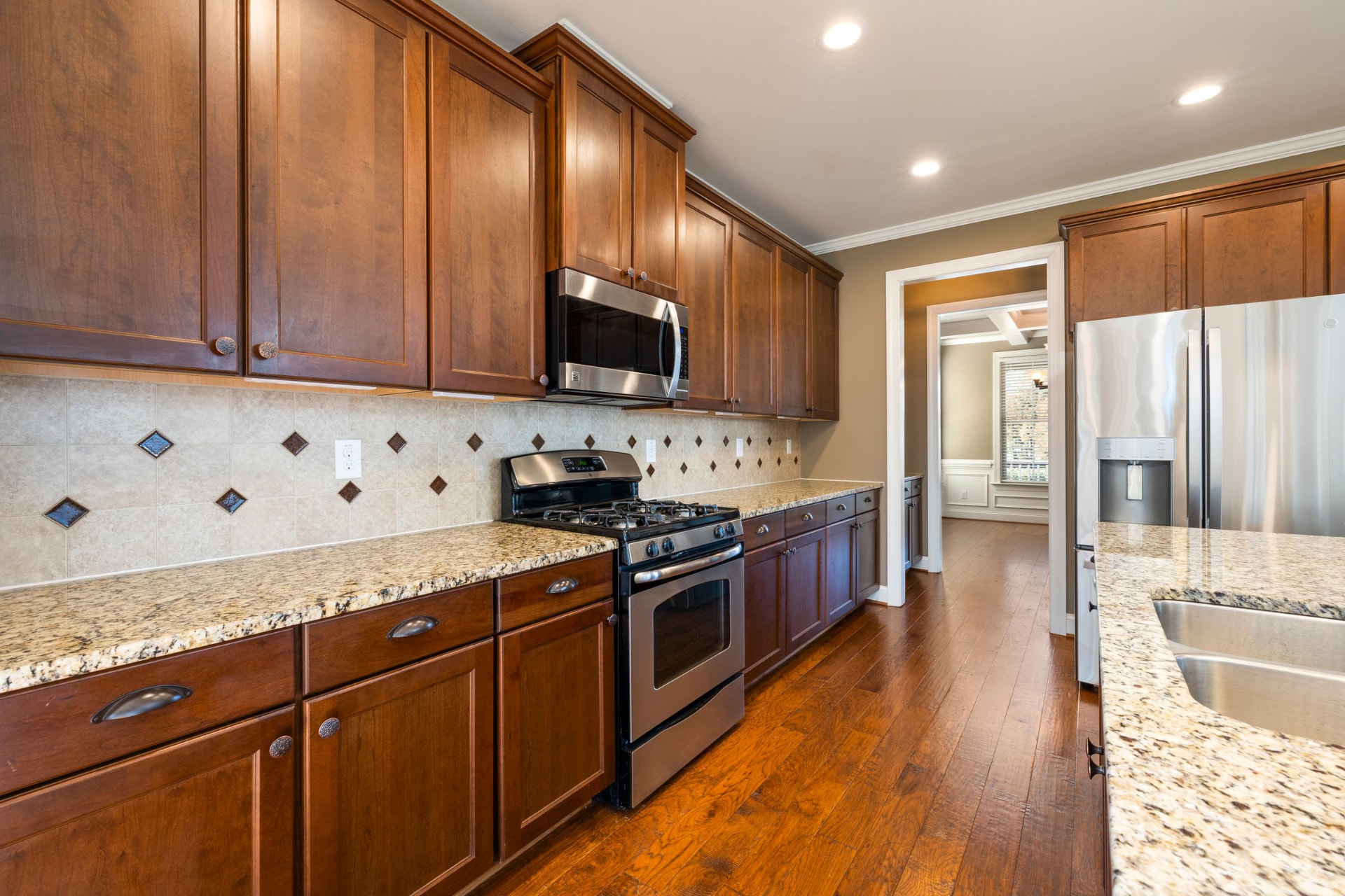 Medium-brown wood cabinets with granite counters and hardwood floors