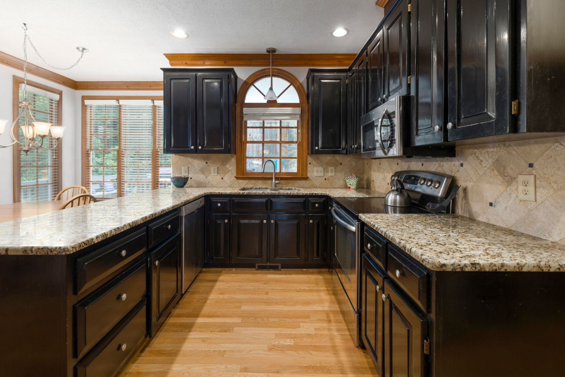 Black cabinetry with granite countertops and a tile backsplash