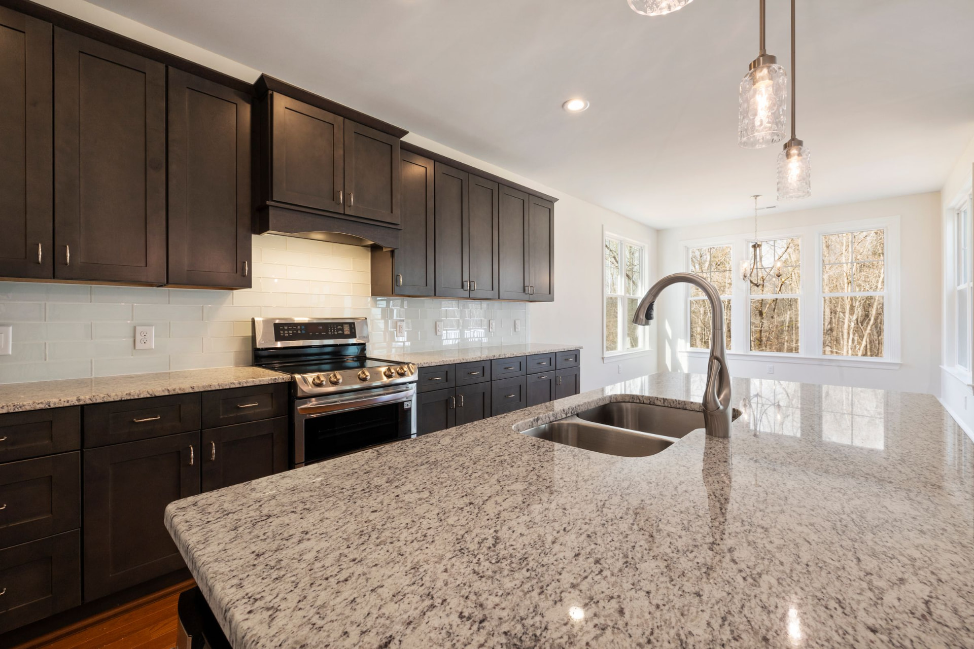 Espresso cabinetry with white subway tile and a granite island
