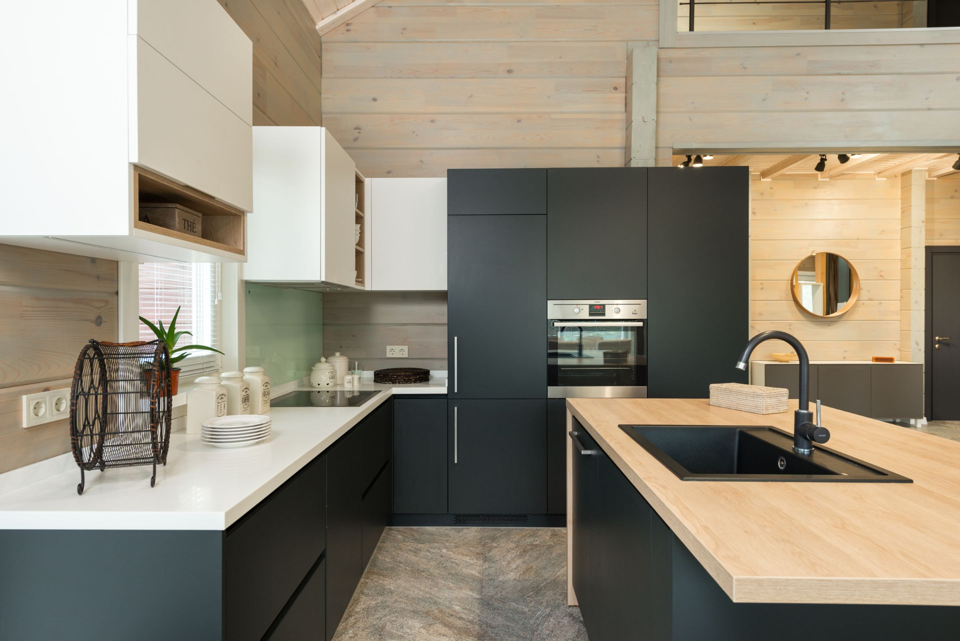 Black and white flat-panel cabinets with pale wood walls and a butcher-block island